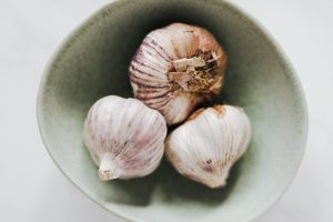 Bowl with whole garlic heads on table