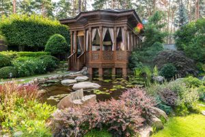 Gazebo near pond and plants with flowers