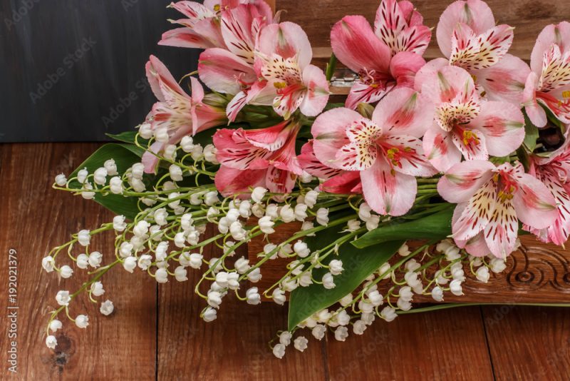 bouquet of pink alstroemerias and wood lilies of the valley in a wooden box